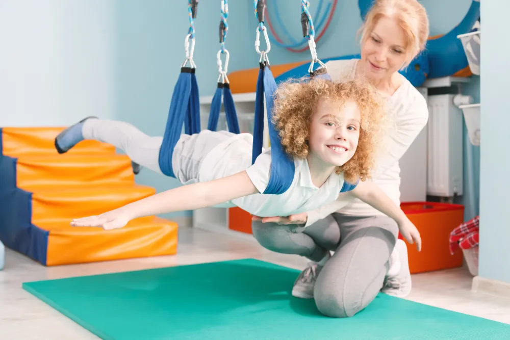 Kobieta huśta dziecko na taśmach do rehabilitacji