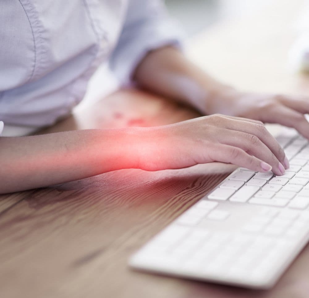 Ból dłoni i objawy zespołu cieśni nadgarstka u osoby piszącej na klawiaturze – graficzna wizualizacja stanu zapalnego w obrębie nadgarstka.