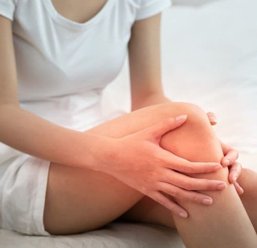 Kobieta trzyma się za kolano z bólu